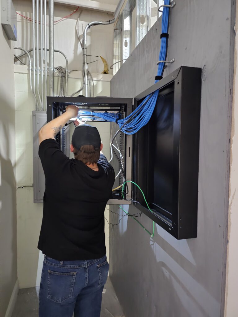 DSI technician mounting and terminating network rack with Cat6 cabling and UniFi equipment during pharmacy installation in Melbourne FL